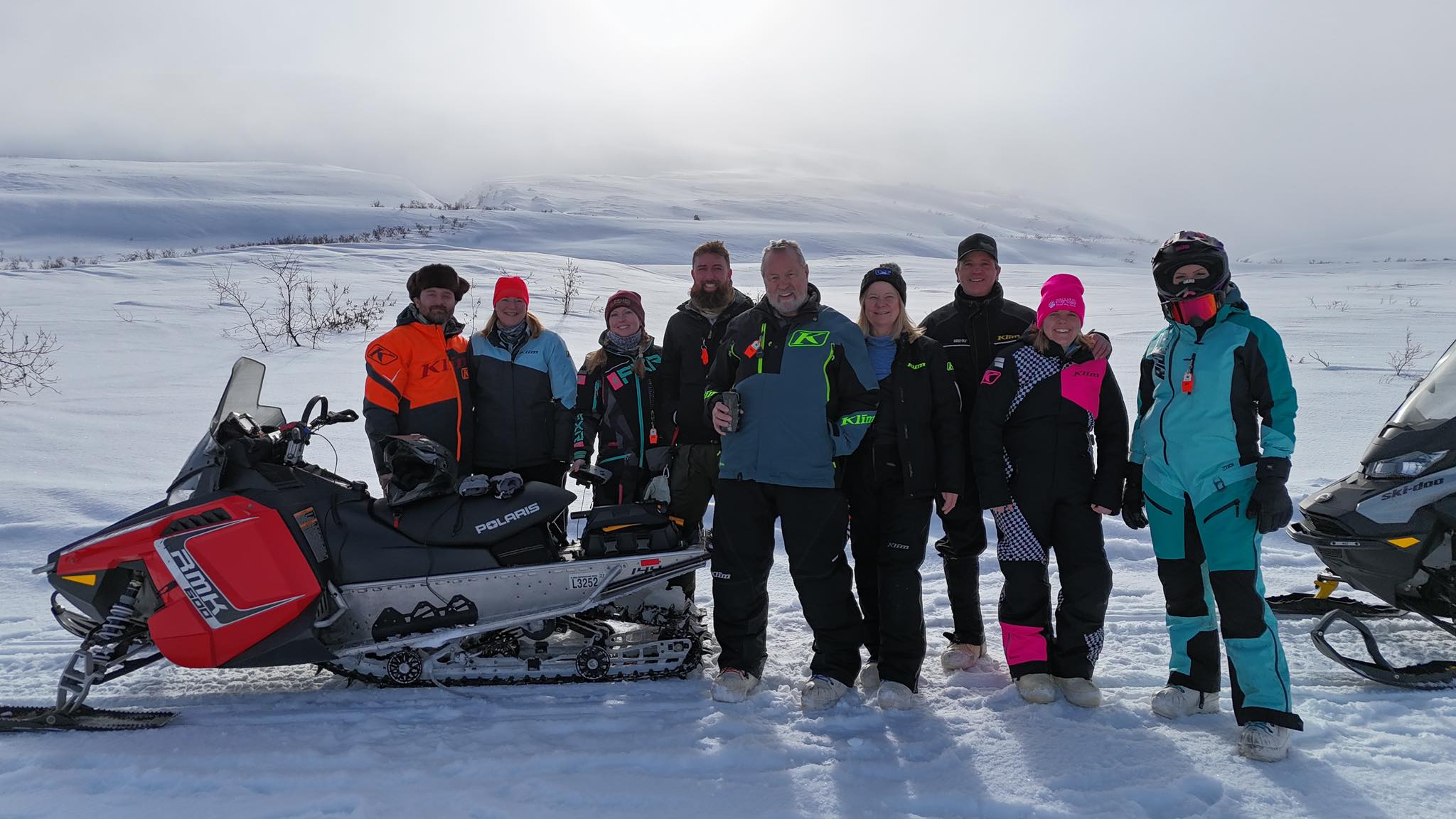 A group of snow mobiles in front of a cold, snowy area